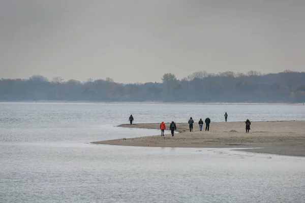 11月の灰色の日にバルト海のトラヴェムンドのビーチで秋の散歩をしている人々 コピースペース 選択された焦点 フィールドの狭い深さ — ストック写真
