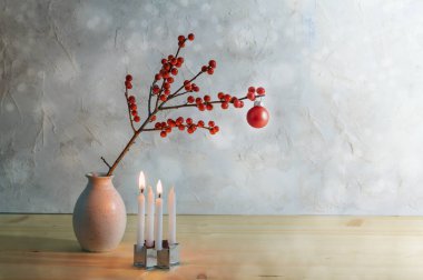Minimalist ikinci kişi, dört küçük mumla geliyor, ikisi yanıyor ve vazoda kırmızı bir noel topu olan bir dut dalı, fotokopi alanı olan karlı arkaplan, seçilmiş odak noktası.