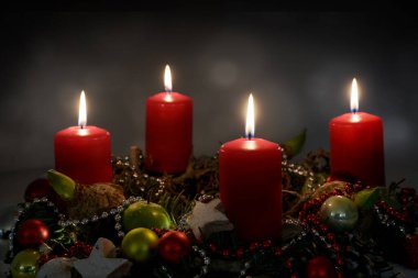 Gece mum ışığı, dört kırmızı mum ve Noel süslemesi ile bir Advent çelengi parçası koyu arkaplan, kopyalama alanı, seçilmiş odak, dar alan derinliği
