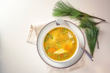 Tavuk, sebze ve maydanozlu sağlıklı köri çorbası, sonbahar ve kış aylarında soğuk algınlığına karşı ev yapımı ilaç, çam dallı hafif masa, fotokopi alanı, yukarıdan üst görünüm, seçilmiş odaklanma.