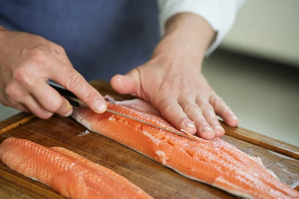 鱼片片 厨师的手在切菜板上用细鱼片刀切去骨头 选定的焦点 狭窄的场地深度 — 图库照片