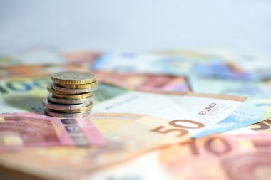 Stack of coins on banknotes in euro currency, concept for economy, business, finance and inflation, copy space, selected focus, very narrow depth of field