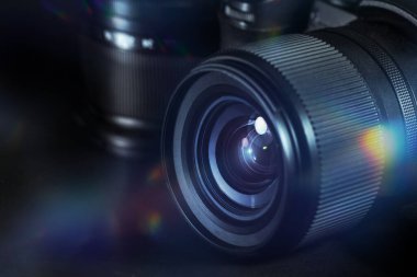 Digital photography, lens of a black camera with reflections and flares against a dark background, technical equipment for business and art, copy space, selected focus, narrow depth of field