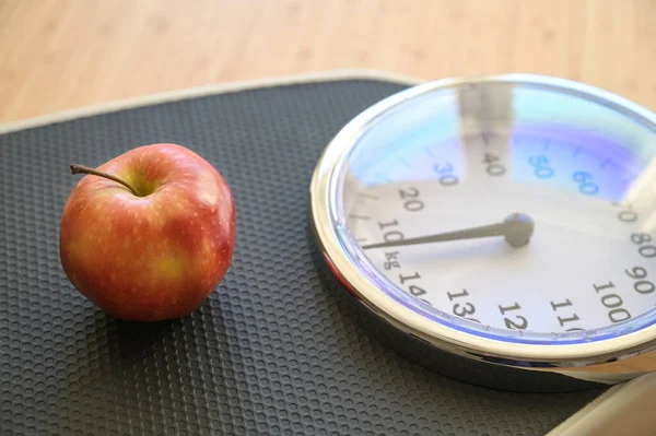 Fresh red apple on an analogue personal scale on a wooden floor, concept for fitness, lose weight diet and healthy eating, copy space, selected focus, narrow depth of field