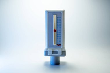 Peak flow meter, medical device that measures the maximum rate of exhalation of a person to monitor lung function and breathing. Light background, copy space, selected focus, narrow depth of field