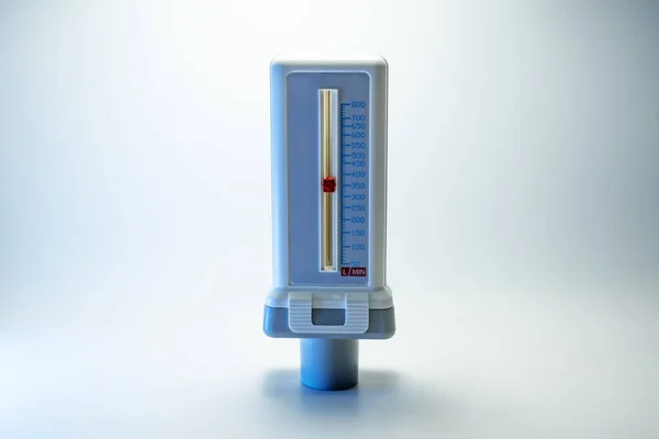 Peak flow meter, medical device that measures the maximum rate of exhalation of a person to monitor lung function and breathing. Light background, copy space, selected focus, narrow depth of field