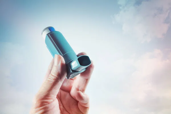 Hand holding an inhaler with spray as emergency medication for an asthma attack, allergy or other lung disease with shortness of breath, copy space, selected focus, narrow depth of field