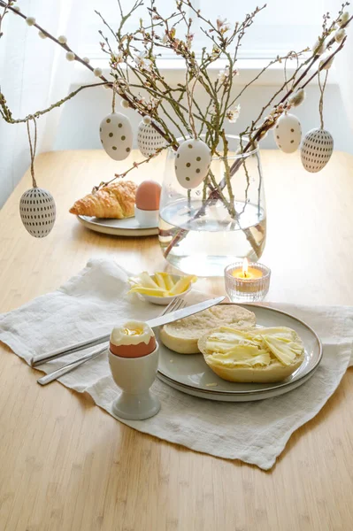 复活节早餐 用鸡蛋 面包卷和黄油 用春枝装饰 并在饭桌上的玻璃瓶中挂上图案彩蛋 复制空间 选定焦点 狭窄的田野深度 — 图库照片