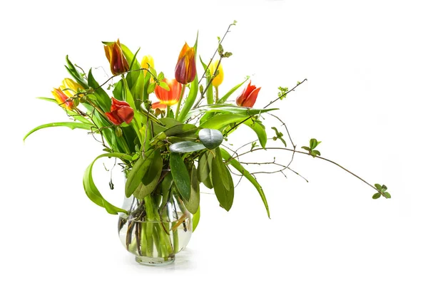 白の背景に小さな影で隔離されたガラス花瓶の花束として春の枝と赤と黄色のチューリップ 休日の装飾やイースターグリーティングカード コピースペース 選択したフォーカス — ストック写真