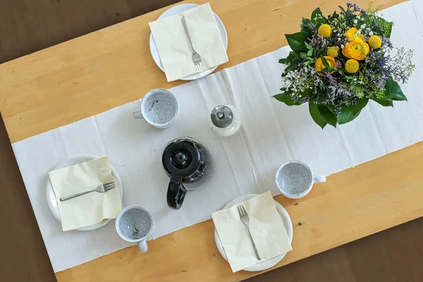 Ξύλινο Τραπέζι Τρία Πιάτα Φλιτζάνια Χαρτοπετσέτες Καφετιέρα Και Ένα Μπουκέτο — Φωτογραφία Αρχείου