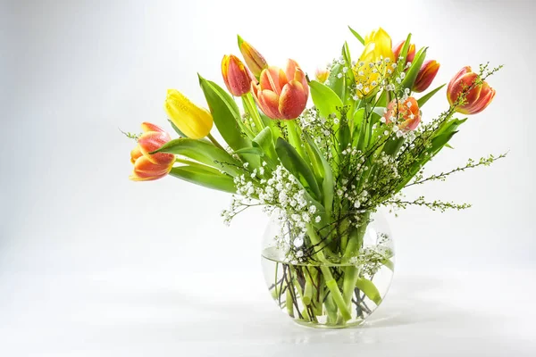 淡いグレーの背景 装飾やイースター バレンタインと母の日のための休日のグリーティングカードに対するガラス花瓶に赤と黄色のチューリップの春の花の花束 コピースペース 選択された焦点 — ストック写真