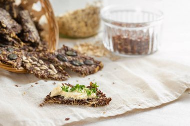 Keten tohumu, yulaf lapası ve çeşitli tohumlardan pişirilmiş sağlıklı çıtır çıtır atıştırmalıklar, tereyağı ve maydanozla süslenmiş hafif bir peçete ve masa, kopya alanı, seçilmiş odak alanı, dar bir alan