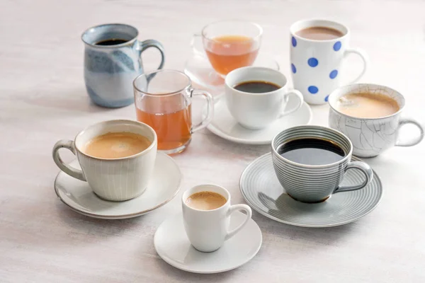 一组不同的杯子和杯子与咖啡和茶水放在一个轻薄的桌子上 选定焦点 狭窄的场地深度 — 图库照片
