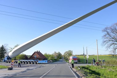 Yel değirmeni bıçağının ağır taşımacılığı, dar bir köy yolu kavşağındaki elektrik hatları, yenilenebilir enerji endüstrisi, mavi gökyüzü, kopyalama alanı, seçilmiş odaklanma gibi engellerden kaçınmak için kaldırıldı.