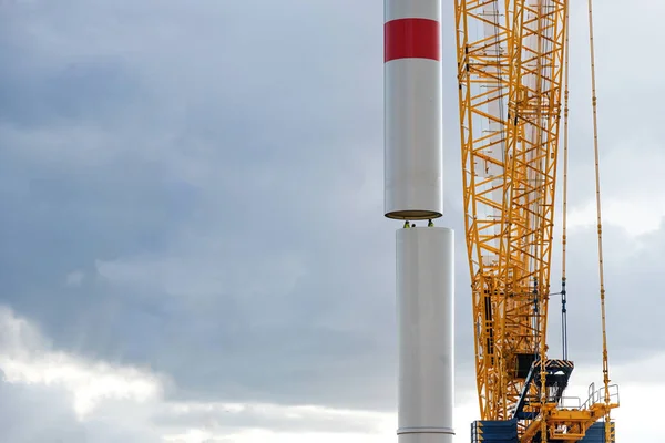 起重机是将风力涡轮机塔体部分移动到第一根管子上 由内部人员引导 精密工作在重工业 发电厂的可再生能源 多云的天空 复制空间 选定的焦点 — 图库照片