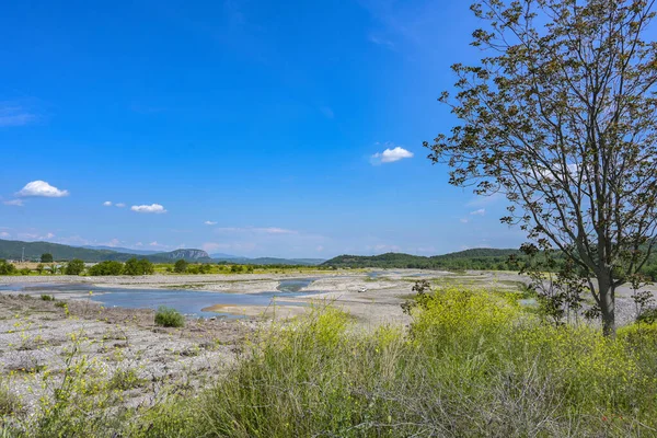 stock image Dried up riverbed of the Pinios near Kalambaka in Thessaly, Greece, low water after heat and drought, potential effect of global climate warming, wide landscape under a blue sky, copy space