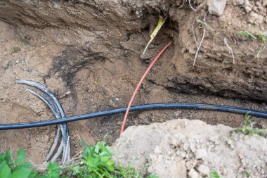 Elektrik ve fiber optikler için farklı kablolar bir evin yakınında, yeni tesisler, kopyalama alanı, seçili odaklanma için kazılırken tehlike altında yatıyorlar.