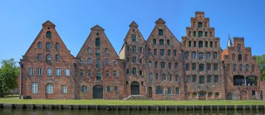 Lubeck 'in Salzspeicher' ı, Almanya 'nın eski Hanseatik kentinde mavi gökyüzü, dönüm noktası ve turistik yere karşı kırmızı tuğlalı mimaride tarihi tuz depolama evleri, panoramik format