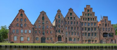 Salzspeicher of Lubeck, historic salt storage houses in red brick architecture against a blue sky, landmark and tourist destination in the old hanseatic town in Germany, panoramic format clipart