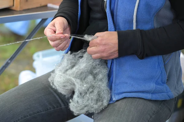 ドイツのクラフト市場で生の灰色のウールを糸に回転させる女性の手は フォーカスを選択 — ストック写真