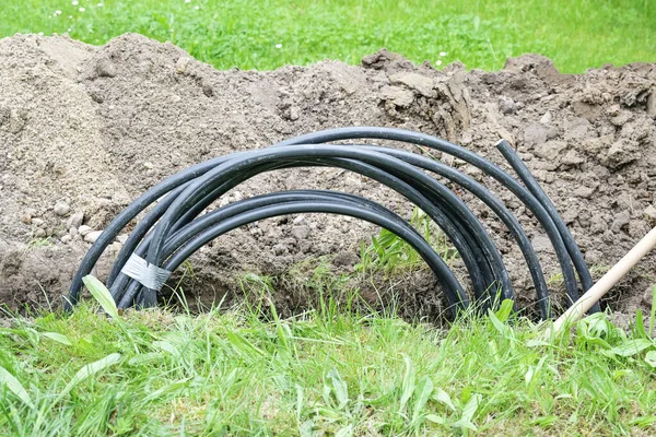 盘绕在草坪狭窄沟里的黑色电力电缆安装房屋连接 能源概念 复制空间 选定焦点 — 图库照片
