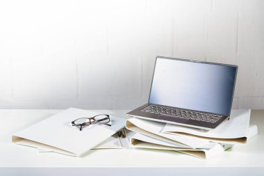 Bir ofis masasındaki birkaç beyaz halka klasöründeki dizüstü bilgisayar ve gözlükler, yönetim ve iş konsepti, kopya alanı, seçili odak alanı, dar alan derinliği