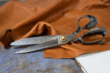 Bir zanaat atölyesinde derinin üzerinde duran büyük, eski bir makas. Kopyalama alanı, seçilmiş odak, dar alan derinliği.
