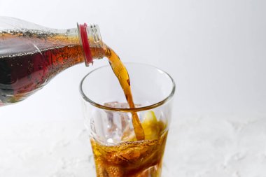 Şişeden taze kolayı buz küpleri ve limon dilimli bir bardağa doldurmak, açık gri arkaplana karşı ferahlatıcı içecek, kopyalama alanı, seçilmiş odak, dar alan derinliği