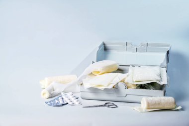 Araba için bir kutuda ilk yardım çantası ve sargı bezi, alçı, hap ve makas, sağlık ve tıbbi konsept, açık mavi arkaplan, kopyalama alanı, seçili odaklanma