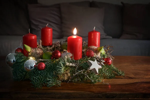 ソファーの前の木のテーブルの燃える赤いろうそくおよびクリスマスの装飾 最初の日曜日のためのお祝いの家の装飾 コピースペース 選択された焦点 フィールドの狭い深さとアドベント — ストック写真