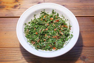 Taboule, Lübnan maydanoz salatası, domatesler, soğanlar ve nane şekeri yukarıdan görülen ahşap bir masa üzerinde, kopyalama alanı, seçilmiş odak, dar bir tarla derinliği.