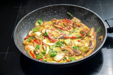 Kızartma tavasında sebzeli Tayland körisi, kırmızı dolma biber, mantar, pak choi, zencefil, zerdeçal ve soğanla tatlandırılmış, hindistan cevizi sütüyle pişirilmiş, seçilmiş odak, dar bir tarla