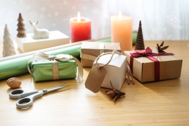 Hediye paketi, hediyeli ahşap masa, makas, kağıt, mum ve Noel süslemesi, evde tatil etkinliği, fotokopi alanı, seçilmiş odak, dar alan derinliği