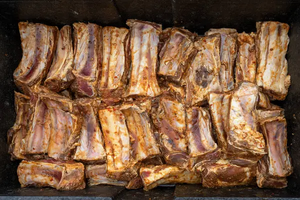 调味和腌制的牛肉排骨被放在一个大的黑色金属碗里 准备与许多客人一起烧烤 从上面俯瞰 选定焦点 图库图片