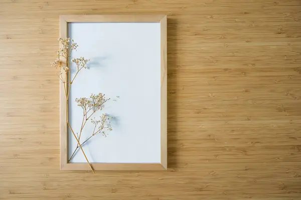 在竹子背景上的空画框上的吉普赛小分枝 简约的日本风格的静谧生活和家居装饰 化妆品的背景 复制空间 选定的焦点 图库照片