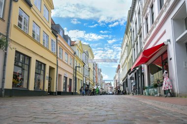 Lubeck, Almanya, 30 Mayıs 2024: Huxsstrasse, tarihi eski kasaba merkezinde mağazaları ve restoranları olan parke taşı caddesi güneşli bir günde, ünlü turizm beldesi, fotokopi alanı, seçilmiş odak noktası