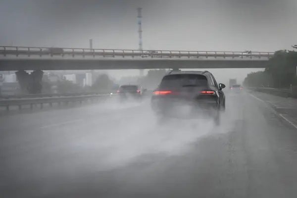 stock image Cars driving too fast in heavy rain on wet roads with poor visibility and the risk of aquaplaning on the highway, dangerous weather for traffic and transportation, copy space, selected focus