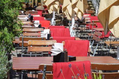 Inviting rustic furniture in a street restaurant or cafe with wooden tables and chairs and red blankets, outdoor gastronomy, selected focus, narrow depth of field