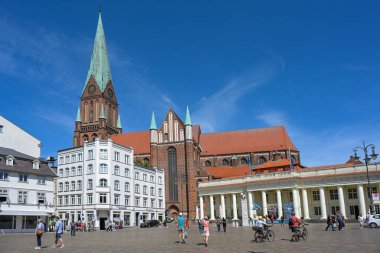 Schwerin, Almanya, 29 Temmuz 2024: Kırmızı tuğla mimarisinde beyaz Kol Binası ve St. Marien katedrali olan pazar meydanı, seyahat ve turizm için ünlü yer, mavi gökyüzü, kopyalama alanı