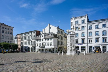 Schwerin, Almanya, 29 Temmuz 2024: Beyaz binalar ve heykeltıraş Peter Lenkon tarafından yapılan Aslan Anıtı tarihi eski Schwerin kasabasının pazar meydanı, mavi gökyüzü, kopyalama alanı