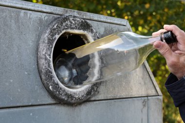 Ham maddelerin geri dönüşümü için cam bir kaba şişe atan bir adamın eli, çevreyi korumak için sürdürülebilir yaşam tarzı, kopyalama alanı, seçilmiş odak noktası