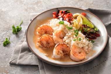 Kabuklu karidesler, gri tabakta pirinç ve sebzeler ve taştan bir arka planda bej peçete, sağlıklı bir ev yapımı yemek pişirme, kopyalama alanı, seçilmiş odaklanma alanı, dar bir alan derinliği 