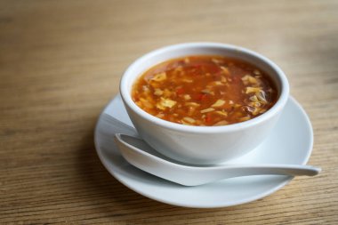 Çin usulü sıcak ve ekşi çorba, çırpılmış yumurta, et ve sebze, porselen kaşıkla porselen kaşık, Asya restoranında ahşap bir masa, kopyalama alanı, seçilmiş odak noktası.