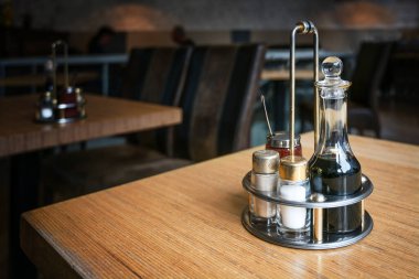 Table set for spices with soy sauce, pepper and salt shakers and hot chili paste on a wooden table in a Chinese restaurant, copy space, selected focus clipart