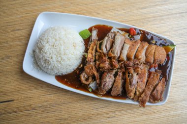 Çin restoranındaki ahşap bir masada soslu ve pirinçli sebzeli kızarmış ördek dilimleri, yukarıdan manzara, kopyalama alanı, seçilmiş odak noktası.