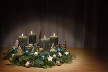 Koyu yeşil mumlu sarı çelenk, dördüncüsü yakılmış, Noel süslemesi, mücevherler, fındık ve tarçın yıldızları, ahşap masa, Noel süslemesi, kopya alanı, seçilmiş odak alanı, dar alan derinliği
