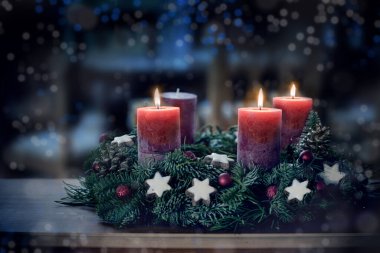 Üçüncü yanan mum ve Noel süslemesi ile Advent çelengi gece mavi ışık, karlı bokeh, fotokopi alanı, renkli fotoğraf, seçilmiş odak, dar alan derinliği