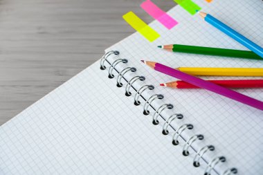 Bir spiral defter parçasındaki renkli kalemler ve gri bir masadaki renkli kalemler, yaratıcı işler veya okul malzemeleri, kopya alanı, seçili odak, dar alan derinliği