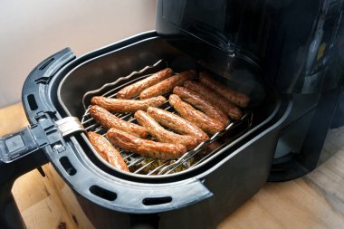 Almanya 'da Nuremberg rostbratwurst adı verilen küçük domuz sosisleri, bir rafta sıcak hava fritözünde kızartılıyor, daha az yağlı ama buruşuk derili, seçilmiş odak noktası, dar bir tarla derinliği olan hızlı kızartma metodu.
