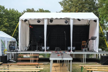 Kırsal kesimdeki bir müzik festivali için inşaat halindeki izleyiciler için açık hava sahnesi ve ahşap banklar seçildi.